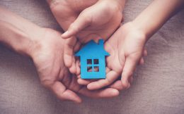 Adult and child hands holding paper house, family home and homeless shelter concept